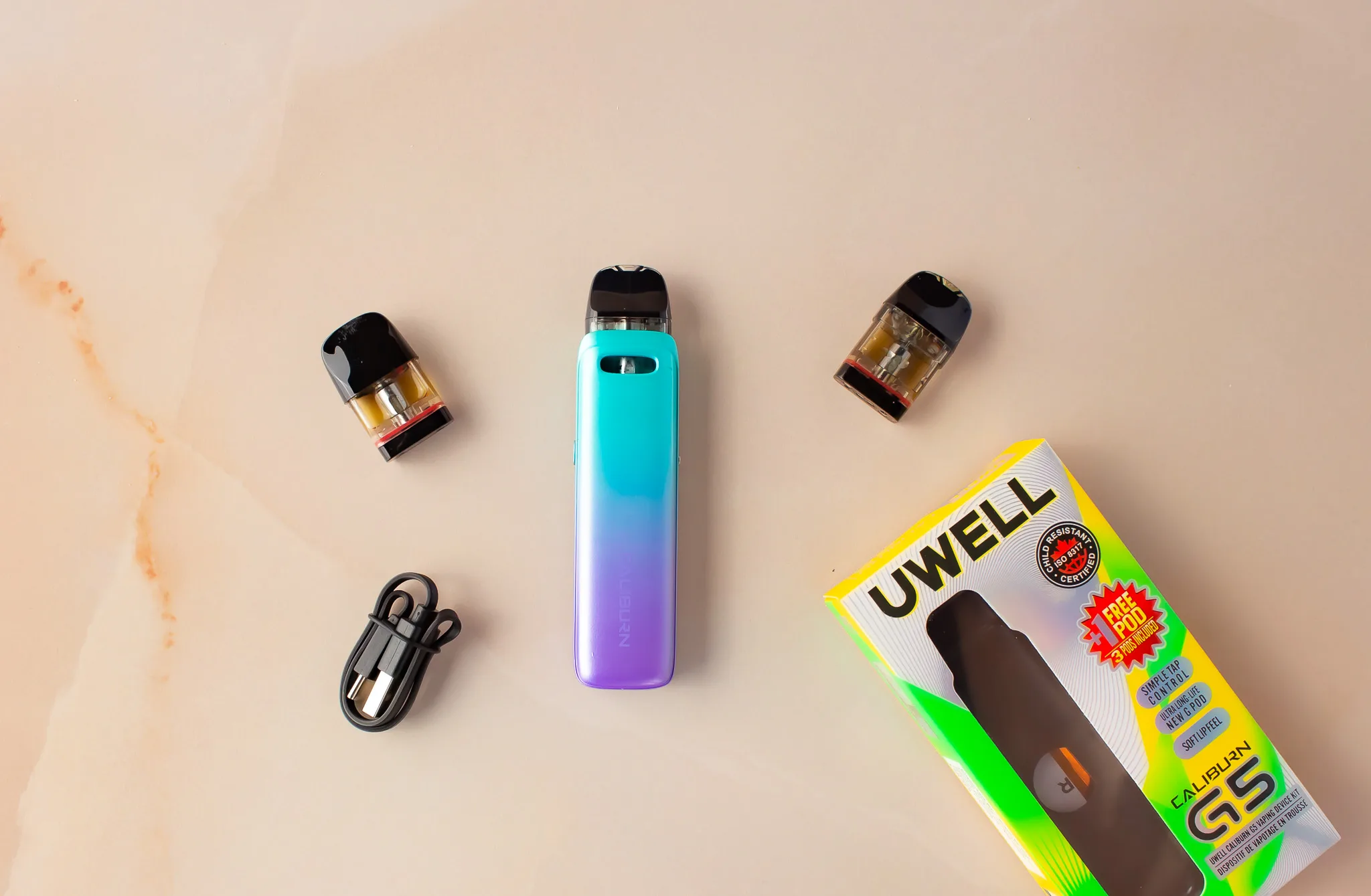 Uwell Caliburn G5 vape kit with device, two pods, charging cable, and packaging on a light background.